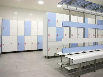 Vestuario con taquillas fenólicas blancas y azules y bancos con perchero