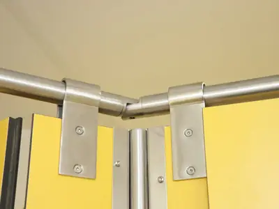 Herraje de acero inoxidable que une el tubo superior con los paneles de una cabina fenólica