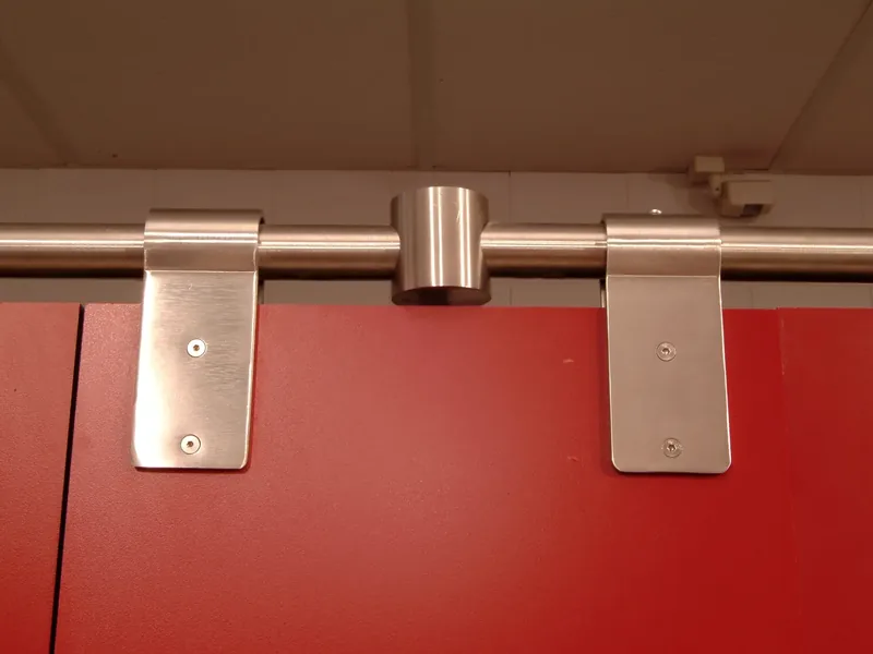 Pinzas y unión de tubo de acero inoxidable sobre el frente de una cabina sanitaria roja