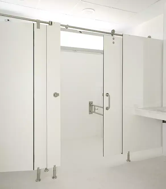 Cabina sanitaria accesible, más ancha, con barra de apoyo junto al inodoro