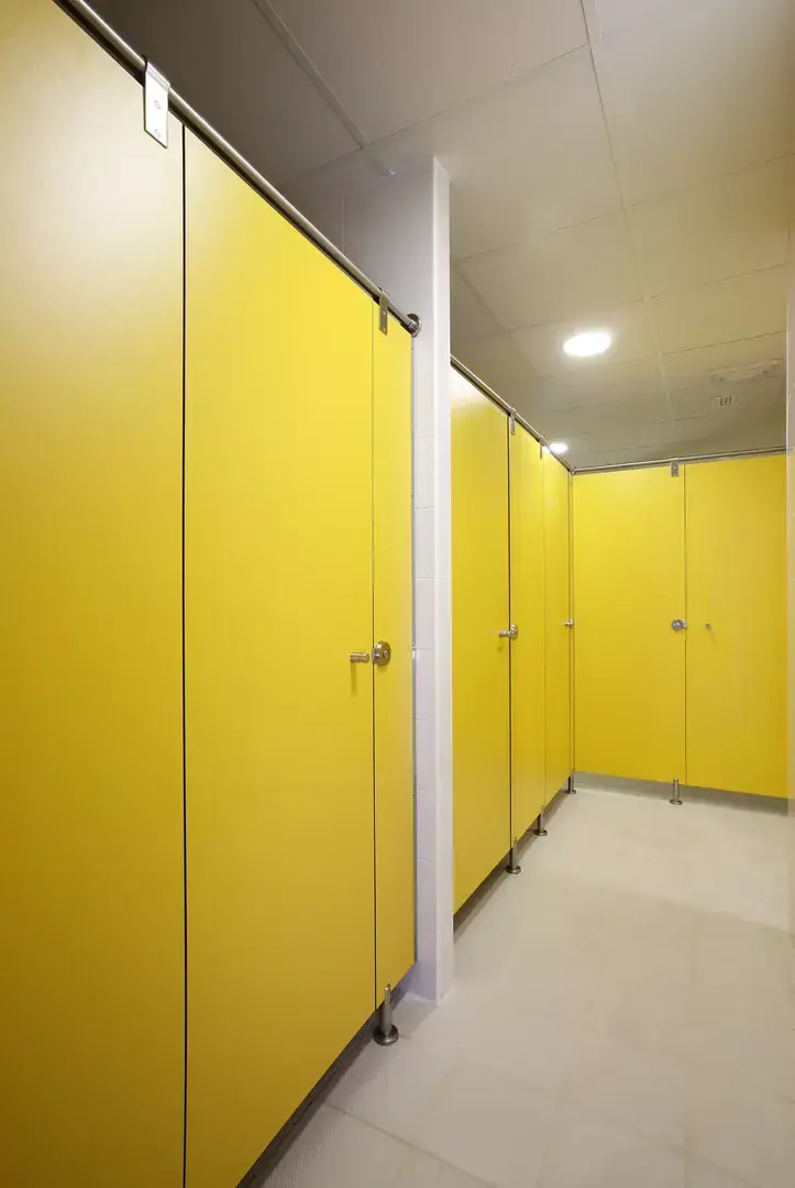 Pasillo de cabinas sanitarias con puertas amarillas