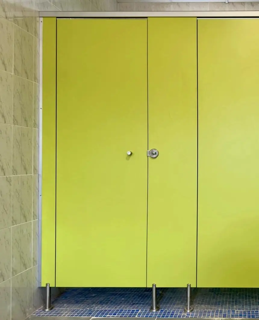 Cabina sanitaria en verde lima con el perfil de coronación de aluminio sobre el canto y pies regulables