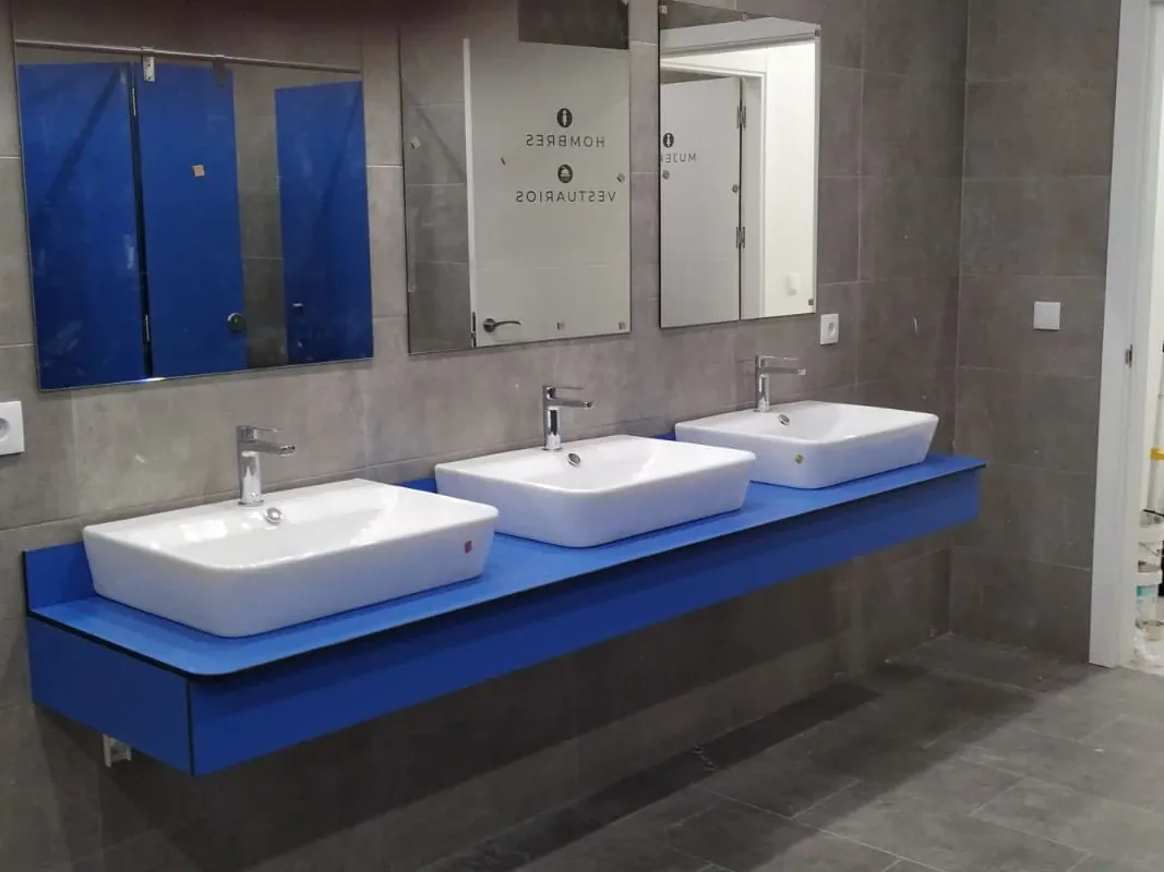 Encimera fenólica azul con tres lavabos de apoyo rectangulares sobre el tablero