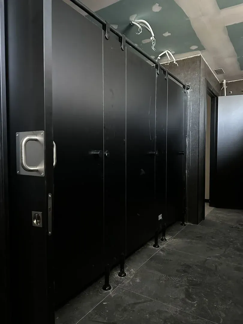 Hilera de cabinas sanitarias negras con el tubo, las pinzas y los pies regulables en negro
