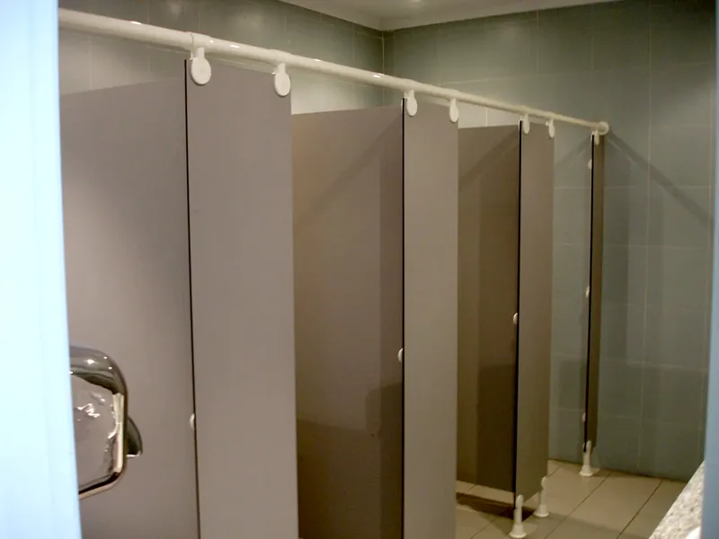 Hilera de cabinas sanitarias grises con el tubo, las pinzas y los pies de nylon blanco