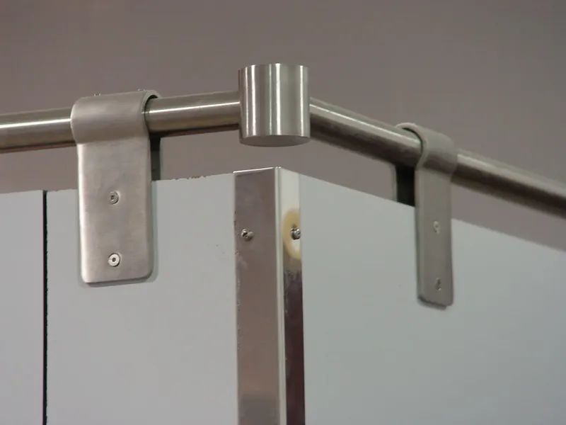Pinzas de acero inoxidable y unión de tubo en T sobre cabinas sanitarias grises