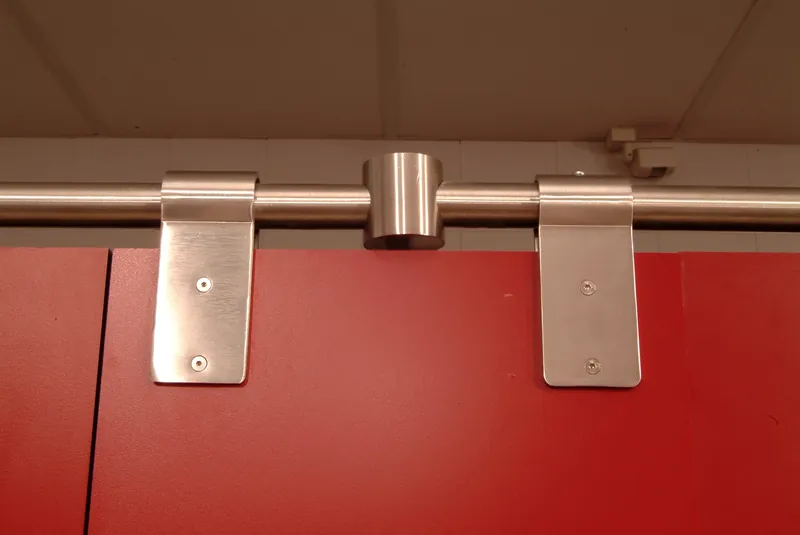 Pinzas y unión de tubo de acero inoxidable sobre el frente de una cabina sanitaria roja