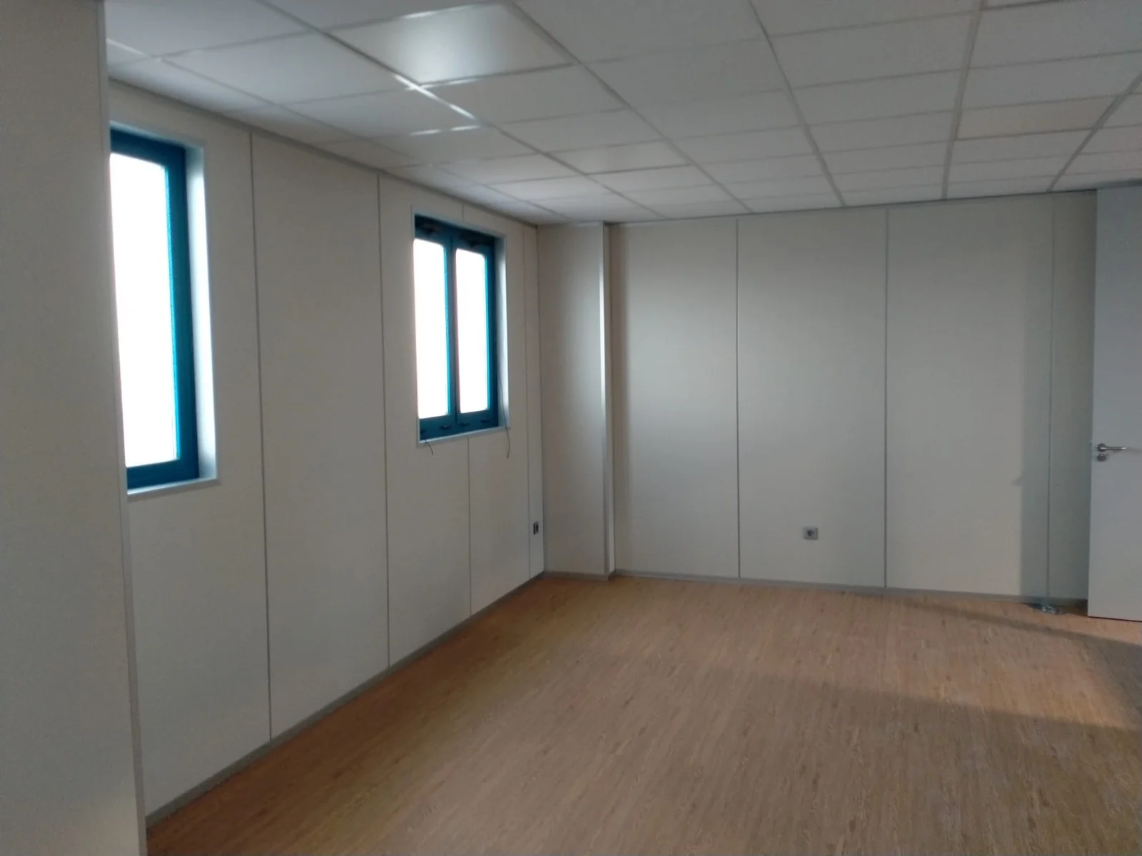 Habitación acabada con paredes lisas y suelo de madera, preparada para instalación eléctrica - Bellum Logistics