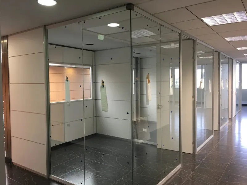 Mamparas transparentes de oficina: despacho acristalado en la esquina de un pasillo