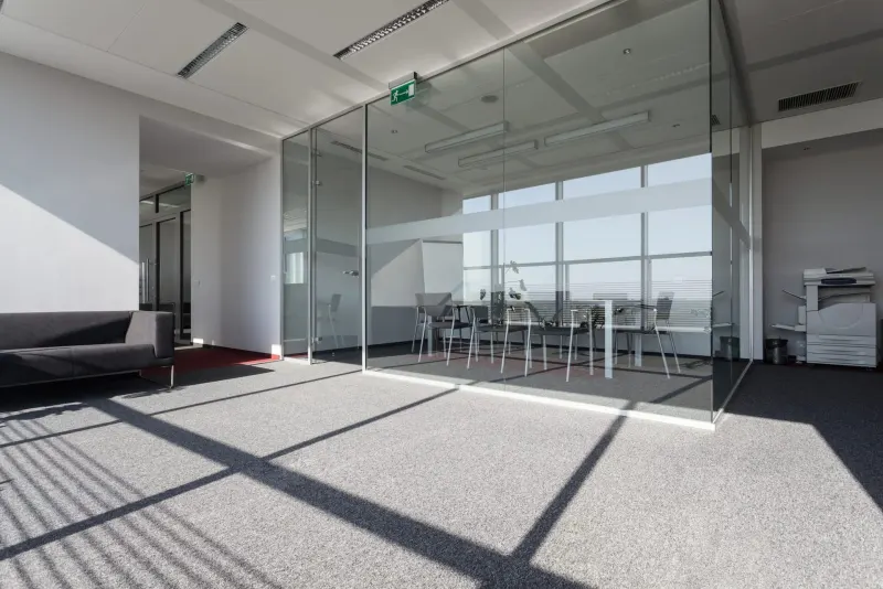 Sala de reuniones cerrada con mampara de cristal y puerta, en una oficina con mucha luz