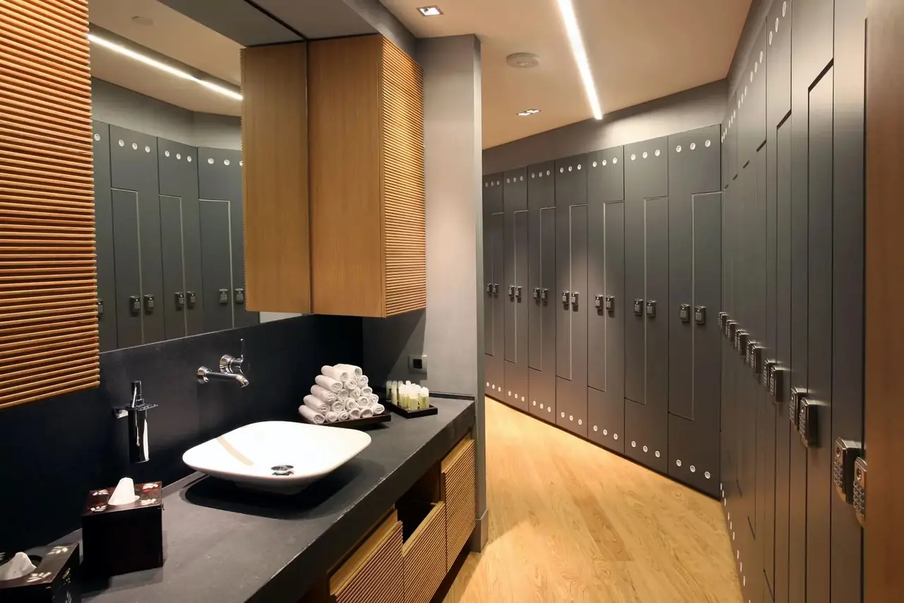 Taquillas fenólicas en gris antracita con puertas en L en el vestuario de un spa, frente a la encimera del lavabo